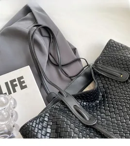 Detail of black woven tote bag featuring classic grid pattern and comfortable shoulder strap