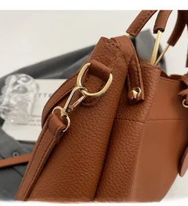 Close-up of brown lychee grain leather with golden lobster clasp and metal hardware