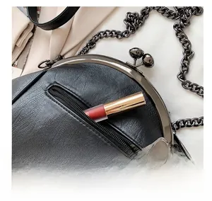 Detail of the back zipper pocket on a black shell crossbody bag with a lipstick for size