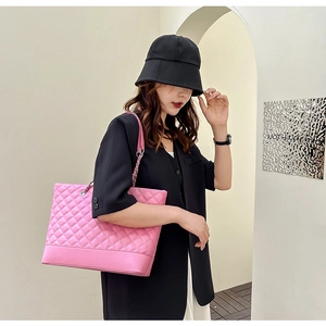 Detail view of pink quilted tote bag with silver chain strap worn by a female model