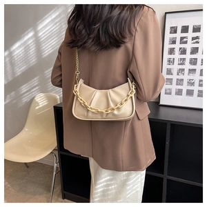 Detail of beige pleated cloud bag with thick chain handle and metal shoulder strap