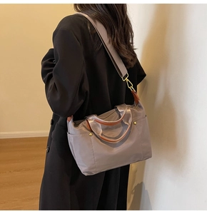 Detail of grey-purple nylon tote with brown leather handles and gold-tone metal hooks