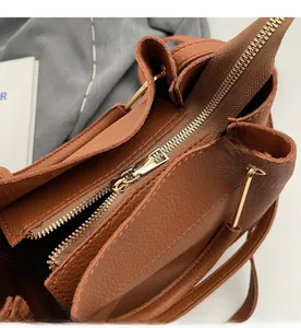 Close-up of smooth gold metal zipper on brown pebble leather tote bag detail
