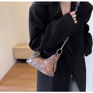 Detail of vintage brown textured crossbody bag with silver chain and geometric stitching