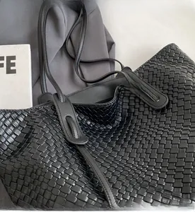 Close-up of black woven leather tote bag with thick texture and durable shoulder strap