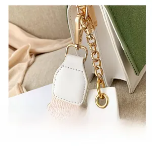 Détail du crochet doré reliant le sac à bandoulière en cuir vert et blanc