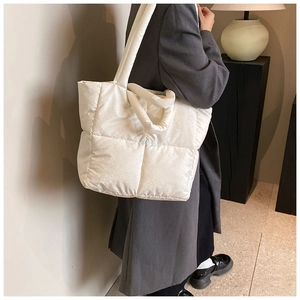 Detail of white quilted puffer tote bag showing voluminous texture and wide strap