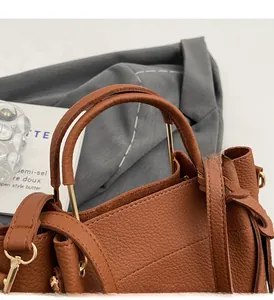 Detail of brown pebble leather handbag showing sturdy handle and gold metal hardware