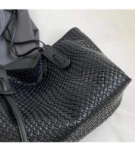 Detail of black woven leather tote bag showing intricate checkered pattern and soft texture
