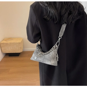 Detail of grey distressed shoulder bag with bold silver chain and metal charm detail