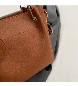 Close-up of brown litchi grain leather and gold metal ring detail on women's tote bag