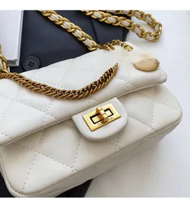 Close-up of white quilted leather crossbody bag with golden metal twist lock and chain