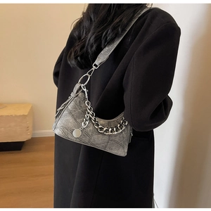 Detail view of grey patchwork crescent bag with silver chain and wide strap on shoulder