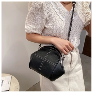 Detail of black leather frame bag with white cross stitching and metal chain strap