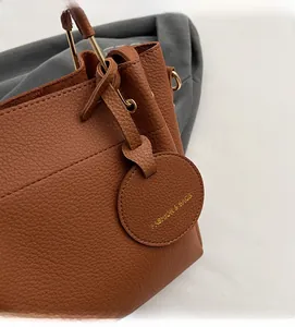 Detail of lychee pattern brown leather bucket bag with gold fashion tag and hardware