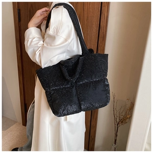 Quilted tote bag detail with glossy finish and detachable shoulder strap on model