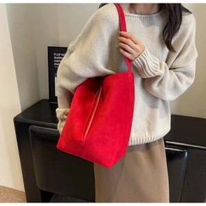 Macro detail of vibrant red suede tote bag showing minimalist design and slim shoulder strap