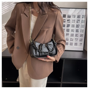 Close-up of black ruched cloud bag with thick chain detail and gold metal shoulder strap