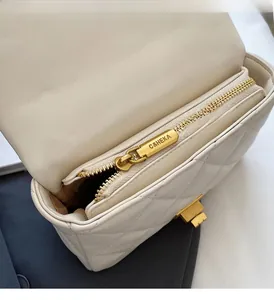 Detail of smooth gold zipper and white quilted leather interior of the crossbody bag