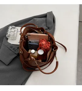 Spacious interior of brown pebbled leather bucket bag holding a tablet and daily essentials