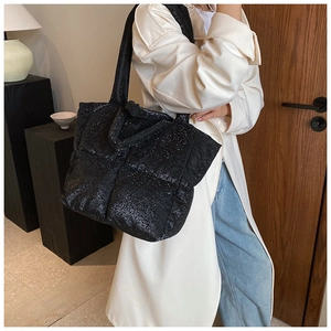 Detail of glossy black quilted tote bag showing shimmering sequin texture and large capacity