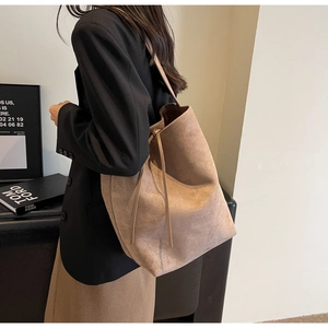 Detail of suede tote bag showing large capacity and side drawstring design on model