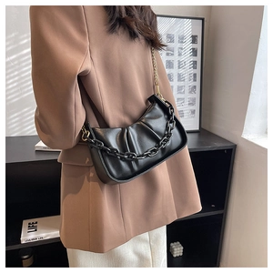 Detail of black pleated cloud bag with thick decorative chain and gold shoulder strap