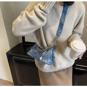 Blue denim texture crossbody bag featuring chunky silver chain and wide strap on model
