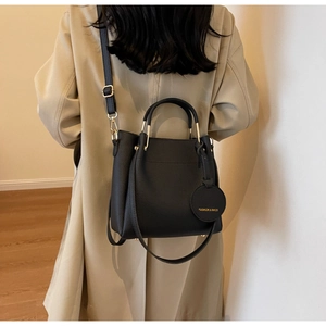 Black lychee leather bucket bag with gold hardware and fashion tag shown on a model