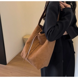 Detail view of large brown suede tote bag with drawstring feature on a model
