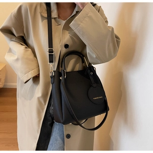 Close-up of black lychee grain leather bucket bag with gold hardware and brand tag