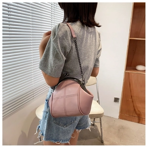 Detail view of a pink crossbody shell bag with retro clasp and metallic chain strap