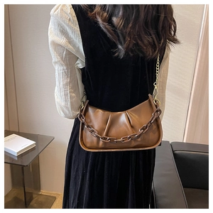 Close-up of brown ruched cloud bag featuring a thick chain detail and gold shoulder strap