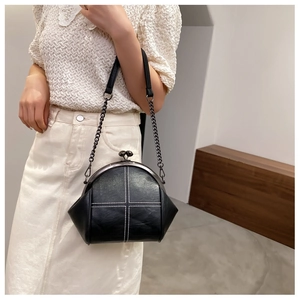 Detailed view of black shell bag featuring white cross stitching and metal chain strap