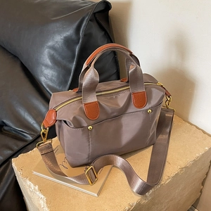 Taupe nylon Boston bag with leather handles and wide shoulder strap on stone stand