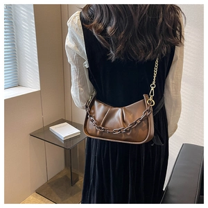 Detailed view of brown ruched crescent bag with resin chain shown on a model