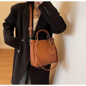 Brown lychee leather bucket bag detail with golden hardware and fashion charm on model