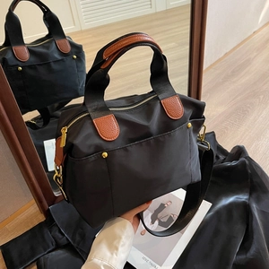 Fashionable black nylon tote bag with brown leather handles and wide fabric strap