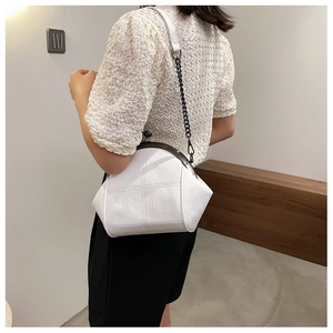 Minimalist white leather shell bag with cross stitching shown on model shoulder