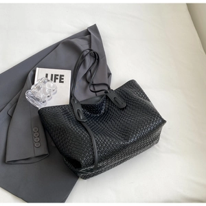 Close-up of black woven leather tote bag with wide checkerboard pattern and flat layout