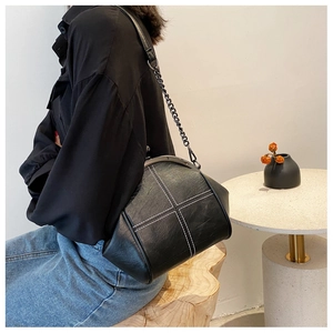 Detail of black shell bag with white cross stitching and retro metal clasp closure