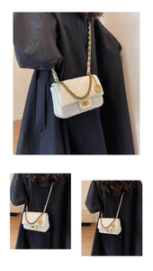 Detail of white quilted leather bag with gold chain strap and luxury metal pendant