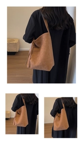 Detailed view of brown suede tote bag featuring decorative side laces and retro style