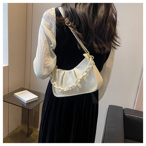 Detail of cream pleated cloud bag with elegant gold and resin chain straps shown on model