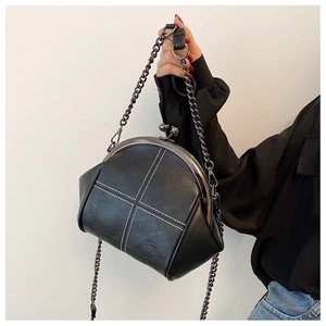 Detail of black pebbled leather shell bag with white cross stitching and metal clasp