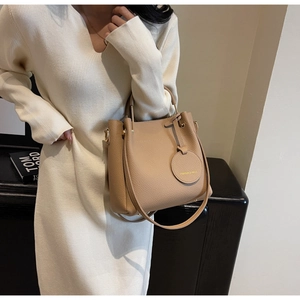 Close-up of camel litchi texture bucket bag with metal handle and fashion charm