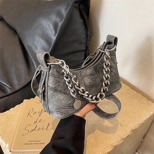 Washed grey denim underarm bag with silver chain and adjustable strap in hand