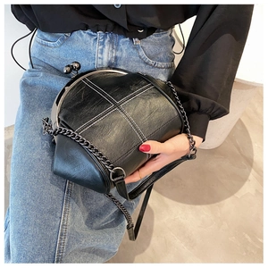 Detail of black shell bag with white contrast stitching and vintage metal kiss-lock