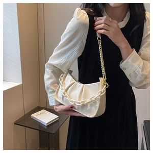 Detail of creamy white cloud bag with chic pleats, chunky plastic chain and gold metal strap