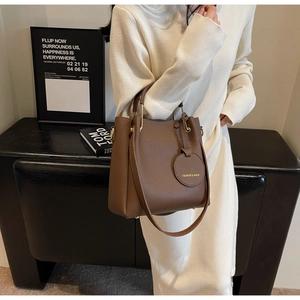 Detail of dark brown lychee leather tote bag with gold hardware on a model outfit